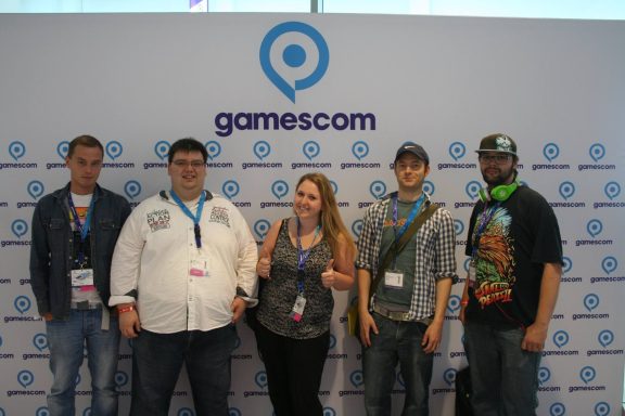Gruppe von fünf Personen vor der Gamescom-Wand mit Logo.