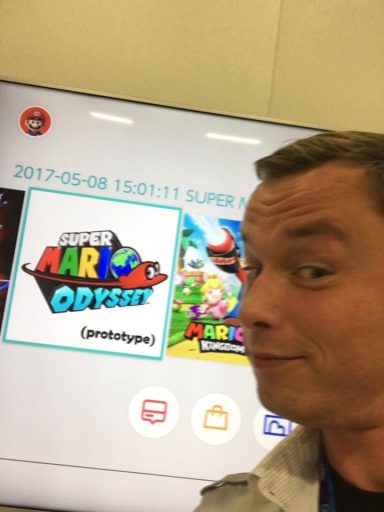 Person macht ein Selfie vor einem Bildschirm mit "Super Mario Odyssey".